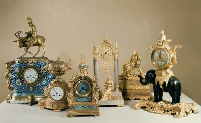 Sammlung von Pendules de Paris, die die unterschiedlichsten Gehäusetypen zeigt, in die das französische Uhrwerk eingebaut werden konnte